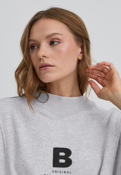 Sivý mikina s textúrovaným čiernym logom "B", rebrovaným výstrihom a mäkkým materiálom. Má uvoľnený strih a minimalistický dizajn.