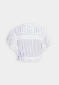 Blusa bianca corta con orlo arricciato, dettagli in pizzo traforato e tessuto morbido con un design a righe testurizzate sulle spalle.