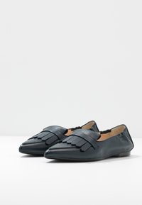 Ballerines en cuir bleu foncé à bouts pointus, avec des franges décoratives sur le dessus et une doublure intérieure douce.