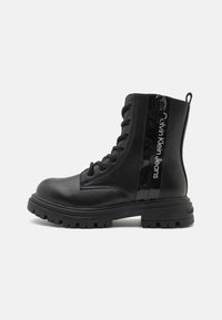 Black combat boots featuring a smooth leather upper, lace-up front, rubber outsole, and side zipper with logo detailing.