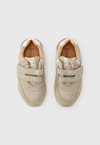 Μπεζ αθλητικά παπούτσια με υλικά από δίχτυ και σουέτ, διπλές λουρίδες με βέλκρο, λαστιχένια εξωτερική σόλα και αρχικό λογότυπο 'b' στη λουρίδα. Μπλε λεπτομέρειες.