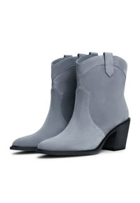Botas de tobillo de ante gris con punta afilada y tacón cuadrado. Presentan una lengüeta y detalles de costura en los laterales.