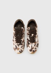 Un paio di sneakers leopardate marroni e beige con lacci marroni scuri su uno sfondo bianco uniforme.