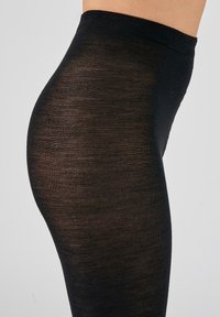 Leggings neri elasticizzati realizzati in un materiale liscio e leggero. Presentano un elastico in vita e una silhouette aderente. Finitura opaca.