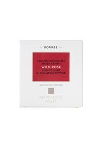 Boîte blanche avec une surface texturée. Étiquette rouge centrée avec un texte blanc indique "Poudre illuminante instantanée Wild Rose". Accents dorés sur les bords.