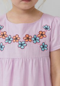 Lila Kleid mit kurzen Puffärmeln, verziert mit bestickten Blumen in Orange, Blau und Schwarz entlang des Ausschnitts und der Raffung des Oberteils.