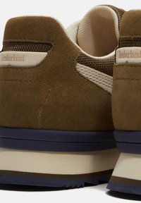 Baskets Timberland en daim marron avec accents en mesh beige, col rembourré et semelle épaisse à plusieurs couches dans des tons bleu marine, beige et marron.