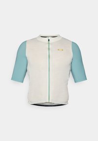 Maillot de cyclisme à manches courtes en blanc et turquoise. Doté d'une fermeture éclair à l'avant, d'un ourlet arrondi et d'un logo discret sur la poitrine gauche. Manches en tissu texturé.