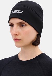 Zwarte sportieve muts gemaakt van rekbaar materiaal, met een gestructureerd oppervlak en een opvallend wit logo. Gladde afwerking, nauwsluitend ontwerp.