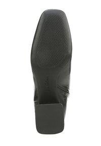 Semelle de chaussure en cuir noir avec un motif texturé pour une meilleure traction et un talon carré. Présente une inscription de logo sur le côté.