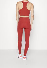 Top corto atlético rojo y leggings de talle alto en una tela suave y elástica, combinados con zapatillas blancas con detalles rojos.