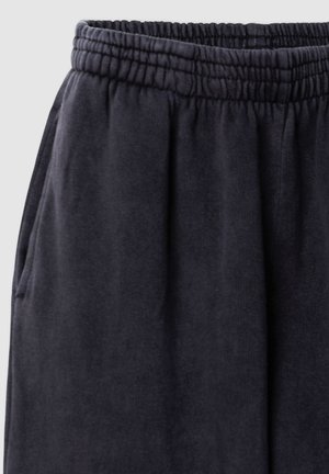 Pantaloni sportivi grigio scuro con cintura elastica, caratterizzati da una texture morbida e tasche laterali. Design semplice, adatto per un abbigliamento casual.
