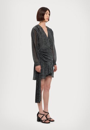 Rochie mini metalizată neagră cu mâneci lungi, talie plisată și fustă evazată. Asortată cu sandale negre cu toc bloc și bretele.