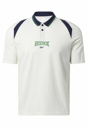 Man draagt een wit Reebok poloshirt met marineblauwe en groene accenten, gecombineerd met marineblauwe shorts met witte gebogen strepen op de zakken.