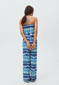 Mnohobarevný, bezramienkový overal s modro-zeleno-bielym tie-dye vzorom; voľný strih, elastický pás a široké nohavice.