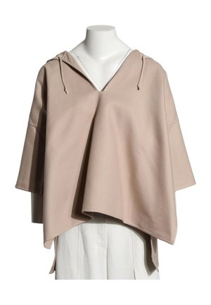 Sweat à capuche beige ample avec manches larges et ourlet asymétrique porté sur un pantalon blanc sur un mannequin sans tête.