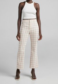 White ribbed crop top paired with light plaid flared pants in soft yellow and pink colors. The pants feature a high waist design.
