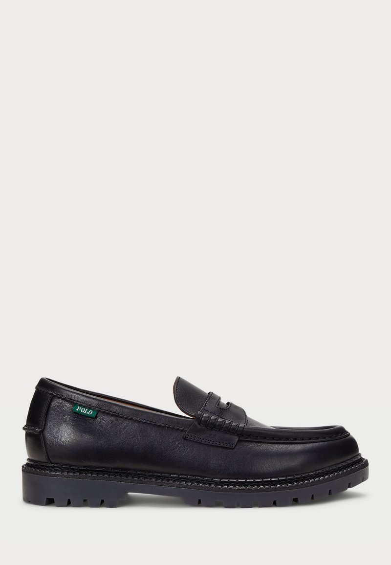 Mocasines de cuero negro con punta estilo mocasín, detalle texturizado en el empeine, suela de goma con tracción y una etiqueta verde "POLO" en el lado.