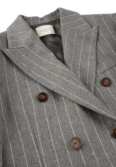Blazer in lana grigia con righe bianche, design doppiopetto, colletto a punta e bottoni marrone scuro. Interno foderato in tessuto grigio.