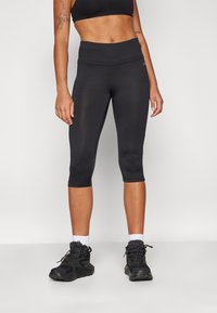 Leggings capri neri realizzati in un materiale liscio ed elastico, con una vita alta e dettagli in rete sui lati.