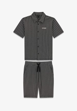 Ensemble chemise à manches courtes boutonnée et short assorti avec motif géométrique noir et blanc et logo "GUESS" sur la poitrine de la chemise.