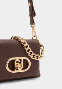 Borsa a tracolla in pelle marrone con una catena dorata e una chiusura dorata prominente con forma ovale e dettagli del logo. Superficie testurizzata.