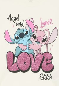 Witte t-shirt met cartoonfiguren Stitch en Angel. De tekst luidt "Angel en Love Stitch" met glinsterende roze letters.