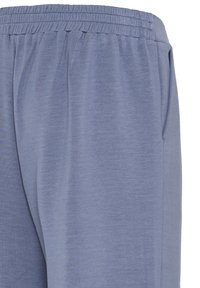 Pantalon de jogging bleu clair en tissu doux, doté d'une taille élastique et de poches latérales, avec une finition lisse et texturée.