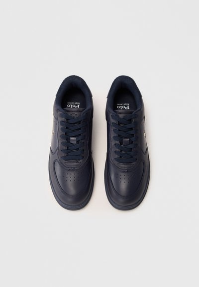 Par črne usnjene superge Polo Ralph Lauren z vezalkami, gledano od zgoraj na beli podlagi.