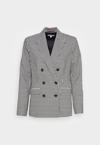 Zwart-wit houndstooth dubbele blazer met brede revers en zes zwarte knopen, weergegeven op een witte achtergrond.