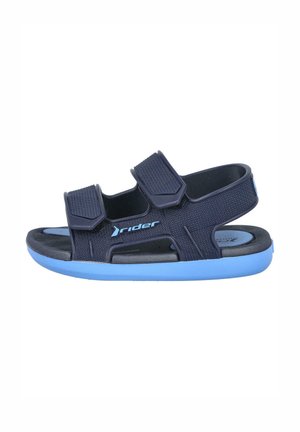 Sandalias azul marino con correas de Velcro ajustables, parte superior de tela texturizada y suela de goma azul claro con agujeros de drenaje y detalle de logo.