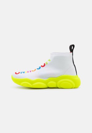 Vysoké tenisky s bílým pleteným svrškem, barevným textem "UNIQUE" a jasně žlutou masivní podrážkou. Obsahují černou patní tabulku.