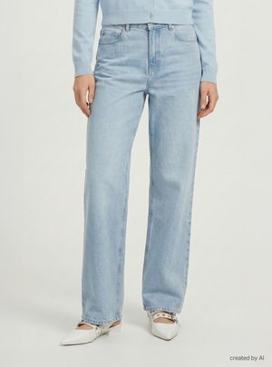 Osoba ubrana w jasnoniebieskie jeansy o prostych nogawkach, jasnoniebieski sweter oraz białe płaskie buty z metalowymi zdobieniami w szpiczastym kształcie.