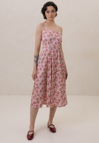 Różowa sukienka midi w kwiaty z regulowanymi ramiączkami, dopasowanym topem i rozkloszowanym dołem. Posiada drobne wzory róż oraz gładkie wykończenie materiału.