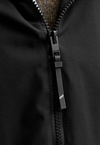 Czarna kurtka z teksturowanej tkaniny, z zamkiem błyskawicznym i kolorowym uchwytem zamka. Minimalistyczny design bez widocznych ozdób.