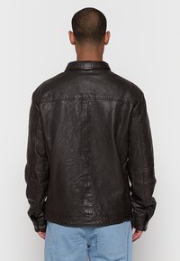 Schwarze Lederjacke mit lässiger Passform, sichtbaren Nähten und klassischem Kragen. Verfügt über lange Ärmel und eine glatte, strukturierte Oberfläche.
