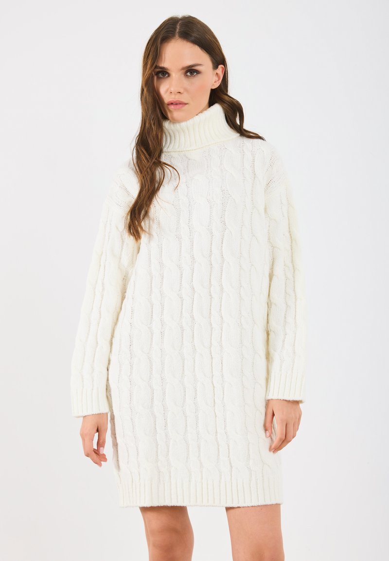 Vestido de cuello alto de punto grueso en blanco roto. Presenta mangas y dobladillo acanalados, con patrones de cable texturizados en toda su extensión. Material suave y acogedor.