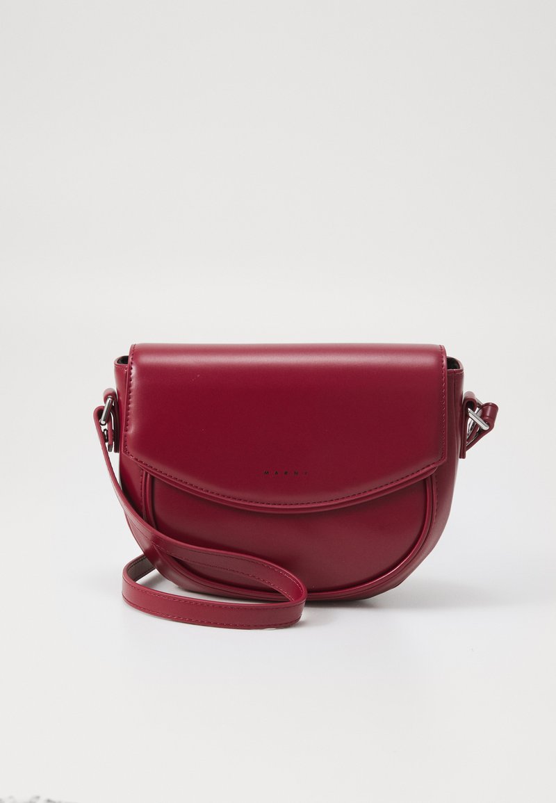 Borsa a tracolla in pelle bordeaux con forma arrotondata, tracolla staccabile e chiusura a pattina, caratterizzata da un marchio minimalista sulla parte frontale.