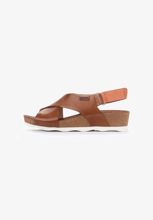Brown leather sandals with crisscross upper design, cork midsole, and white rubber outsole. Adjustable heel strap for a secure fit.