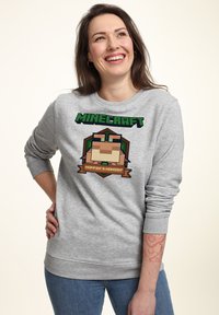 Felpa grigia a girocollo con grafica di Minecraft che presenta personaggi, la scritta "Hoppin' & Hangin'" e polsini a costine. Tessuto dal tocco liscio.