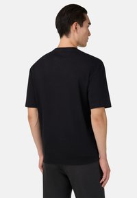 Černé bavlněné tričko s volným střihem, krátkými rukávy a kulatým výstřihem. Má jednoduchou, jednobarevnou a minimalistickou desku.