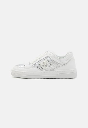 White sneakers with a smooth leather upper, featuring silver rhinestone accents and a textured side design. Lace-up closure and rubber sole.