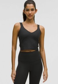 Sort atletisk crop top med V-hals og brede stropper. Fremstillet af glat, strækbart stof med subtile prikmønstre.