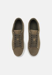 Brune semskede sneakers med rund tå, flade snørebånd og tekstureret overflade. Grå gummisål og præget mærkelogo på indersålen.
