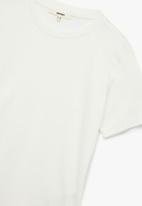 Weißes Baumwoll-T-Shirt mit Rundhalsausschnitt und kurzen Ärmeln, das über eine glatte Textur und ein minimalistisches Design verfügt. Etikett sichtbar im Kragen.