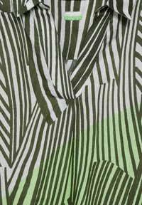 Camicia verde e bianca con motivo a righe verticali di larghezze variabili. Design a V con una texture liscia e etichetta al colletto.
