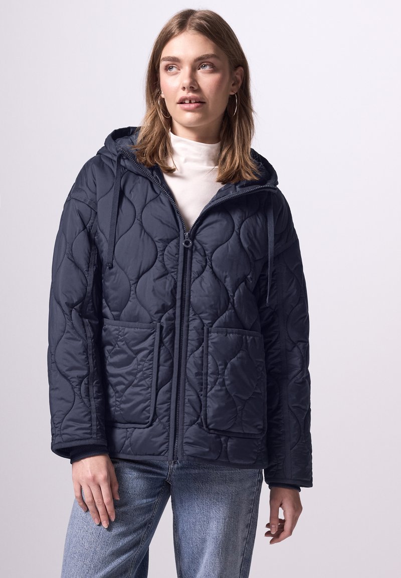 Giacca puffer trapuntata blu navy con cappuccio, maniche lunghe, chiusura con zip e tasche frontali. Caratterizzata da una texture liscia e un design aerodinamico.