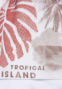 Weißer Stoff mit einem rot-braunen Blattmuster und strukturierten Details. Enthält den Text "TROPICAL ISLAND" in Braun.