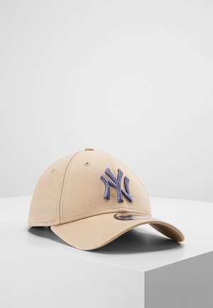 Beige baseball cap with a curved brim, featuring a purple embroidered "NY" logo on the front and a smooth fabric texture.
