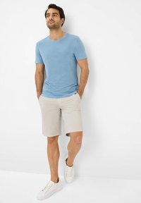 Lichtblauw katoenen T-shirt met korte mouwen, gecombineerd met beige shorts en witte sneakers. Eenvoudig ontwerp, ronde hals en een relaxte pasvorm.